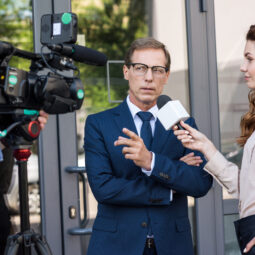 professional cameraman and news reporter talking with serious businessman