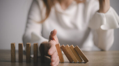 Risk and Strategy in Business, Hand stopping wooden block domino business crisis effect or risk protection concept, prevention and development to stability